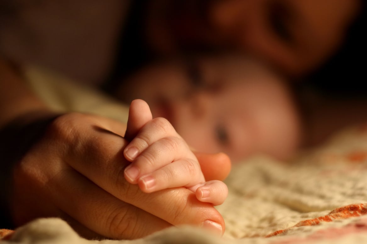 a parent holding their child's hand in the dark