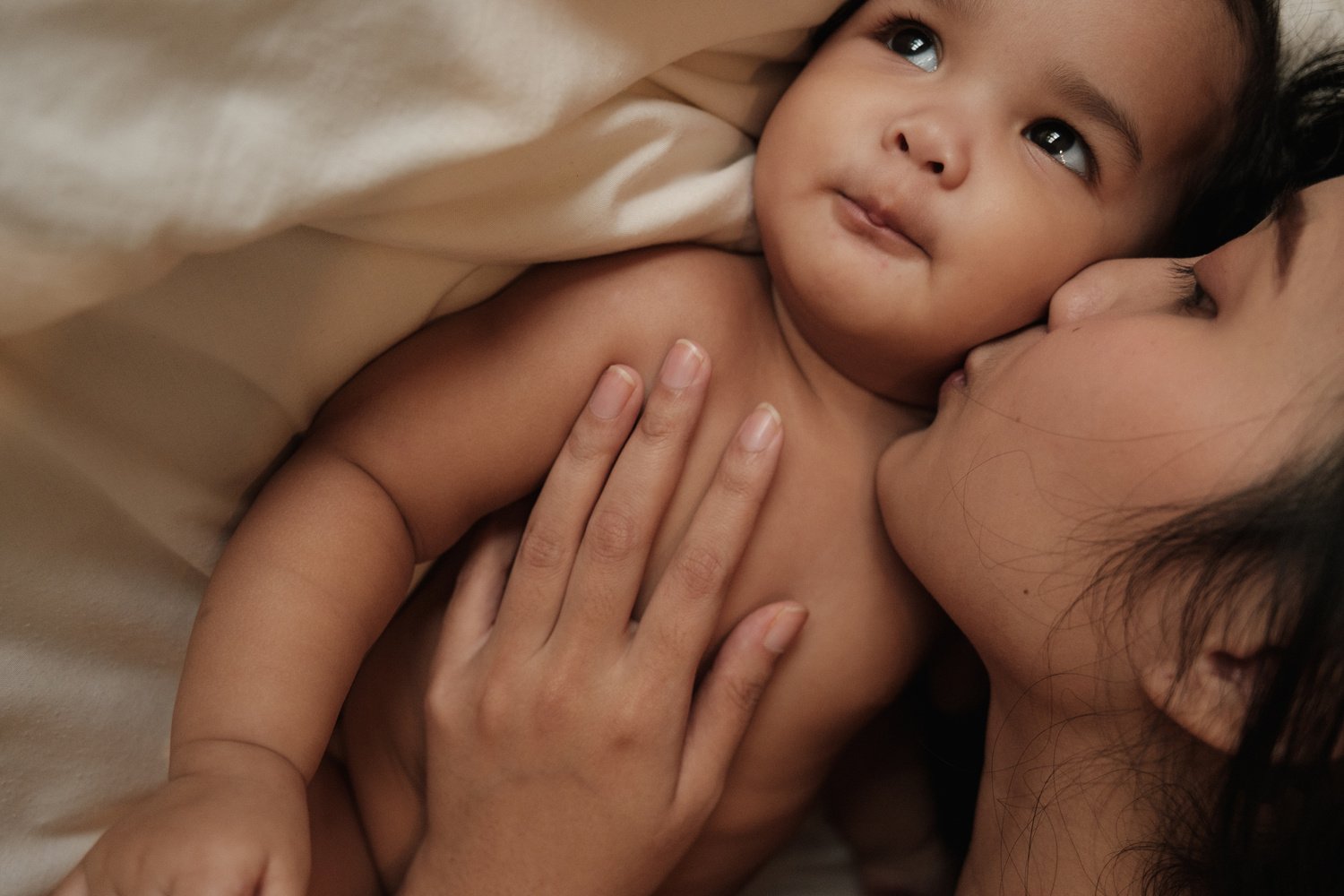 a person is kissing a baby on the cheek